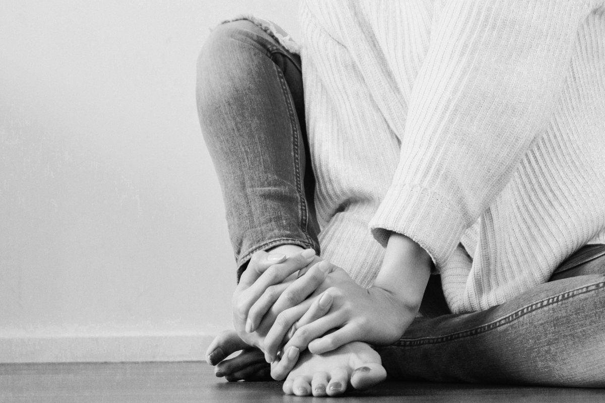 person holding foot due to plantar fasciitis pain